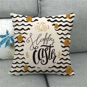 Linen square pillowcase with Happy Easter print and golden eggs on a grey sofa