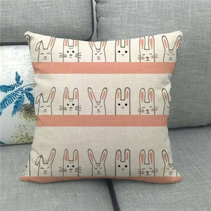 Detail of linen pillowcase with cute cartoon rabbit illustrations on a gray sofa