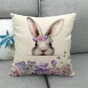 Funda de cojín de lino con conejo de Pascua y corona floral en sofá gris