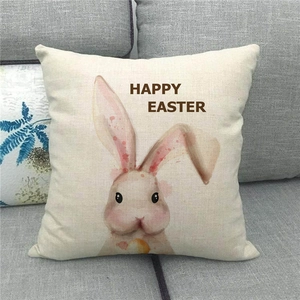 Detalle de funda de almohada de lino Happy Easter con conejo acuarela en sofá gris