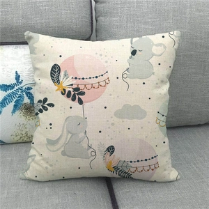 Close-up of linen pillowcase with cute rabbit, koala, and pink balloon on a gray sofa