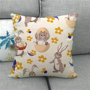 Linen Easter cushion cover with bunny and egg print displayed on a grey sofa