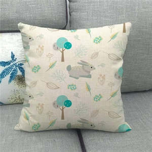 Close-up of linen Easter pillow cover featuring cartoon rabbit and trees on grey sofa