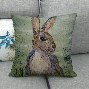 Detailed view of hand-painted rabbit linen pillowcase on a gray fabric sofa