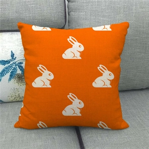 Close-up of linen pillowcase with white rabbit patterns on vibrant orange fabric