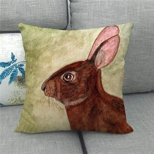 Easter linen pillowcase with watercolor bunny print on a gray fabric sofa