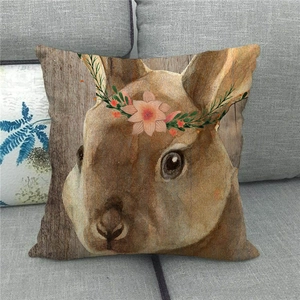Close-up of linen pillowcase with bunny and flower crown on a grey fabric sofa