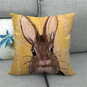 Artistic hand-painted rabbit on yellow linen pillowcase displayed on a grey sofa