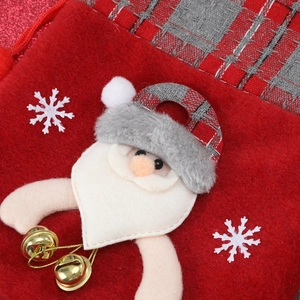Detail of Christmas stocking with Santa embroidery, plaid trim and small gold bells
