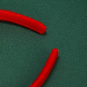Close-up of soft red plush fabric trim on a Christmas headband with festive green background