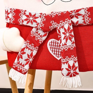Detail of red knitted Christmas chair cover featuring snowflake scarf and heart patch