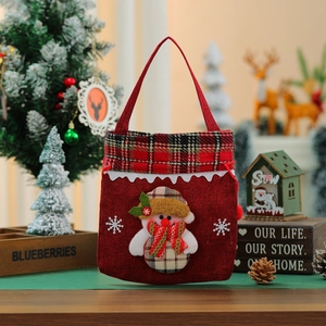 Close-up of a festive red Christmas gift bag with a snowman applique and plaid trim