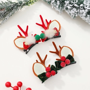 Détail de pinces à cheveux bois de renne de Noël avec pompons et baies rouges festives