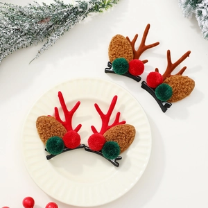 Détail de pinces à cheveux bois de renne avec oreilles en peluche et baies de Noël sur plat
