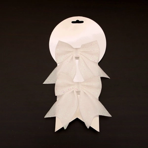 Detail view of two white glitter Christmas bows on a hanging display card for tree decor