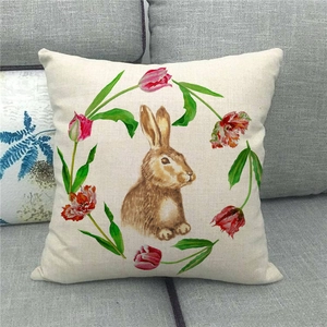 Detalle de funda de cojín de lino con conejo y corona de tulipanes en sofá gris
