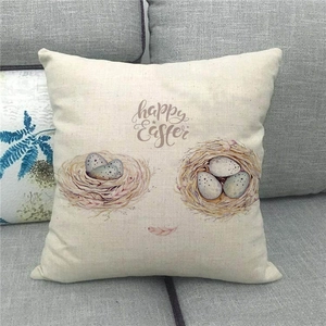 Close-up of linen Happy Easter throw pillow with nest and blue eggs on a sofa