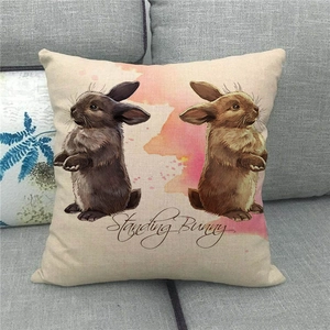 Easter linen pillow cover with watercolor standing bunnies on a grey sofa