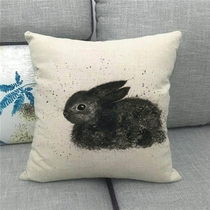 Close-up of linen pillowcase featuring artistic black ink rabbit print on a sofa