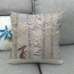 Linen Easter pillow cover with bunny and forest pattern on a grey fabric sofa