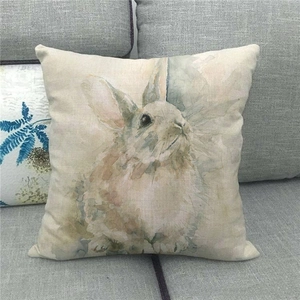 Close-up of linen Easter pillowcase with watercolor bunny pattern on a grey sofa