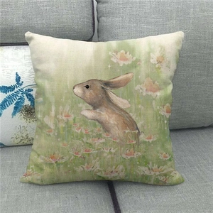 Close-up of linen pillowcase with rabbit and daisy print on a grey fabric sofa