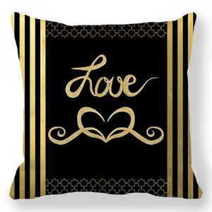 Détail d'une housse de coussin noire avec inscription Love dorée et motifs