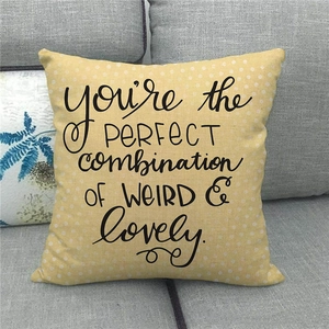Yellow linen throw pillow with white polka dots and artistic text on a gray sofa
