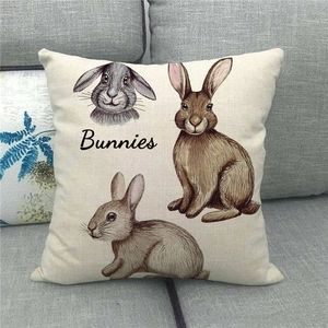 Linen Easter pillow cover with bunnies illustration on a gray fabric sofa