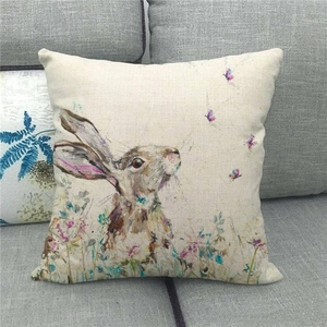 Detail of linen pillowcase with watercolor rabbit and butterflies on a grey sofa