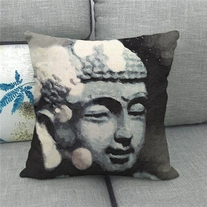 Detail of stone-carved Buddha head linen pillowcase on a grey fabric sofa