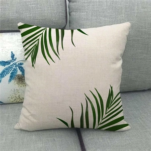 Close-up of linen throw pillow cover with green tropical palm leaf print on a gray sofa