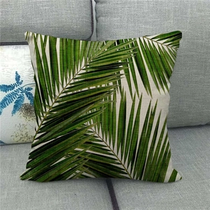 Detail of tropical palm leaf pattern on linen throw pillow case on a gray sofa
