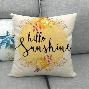 Detail of linen pillowcase with hello sunshine print and floral motifs on a sofa