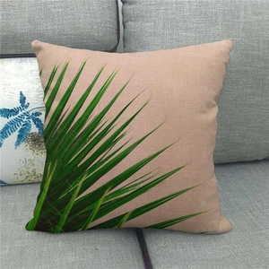 Detail of tropical palm leaf print on a textured linen pillowcase on a grey sofa