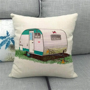 Detail of linen square pillow cover featuring a retro camper trailer design on a gray sofa