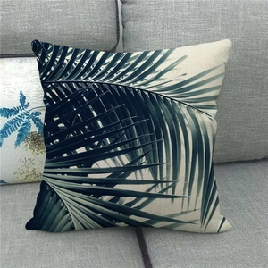 Close-up of green palm leaf print on beige linen pillowcase texture on a sofa