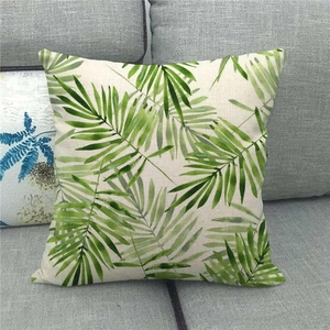 Close-up of tropical green palm leaf print on linen throw pillowcase on a grey sofa