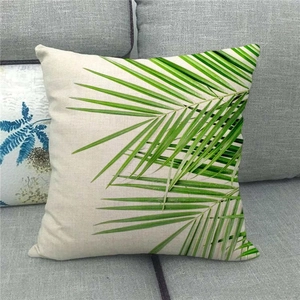 Macro detail of the woven linen fabric and green palm leaf print on square cushion cover