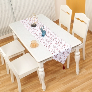 Close-up of a white Christmas table runner with red stars, wavy edges and red tassels