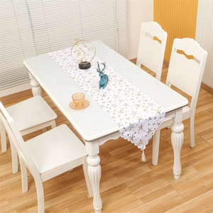 Close-up of white Christmas table runner with gold stars, wavy edges and tassels