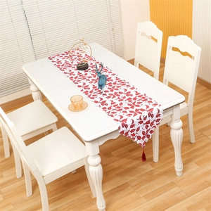 Christmas table runner with red holly berry print and burgundy tassels on white table