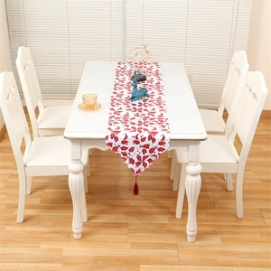 Close-up of white Christmas table runner with red holly embroidery and silk tassel