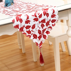 Detail of Christmas table runner with red holly leaves, berries, and fringed edge tassels