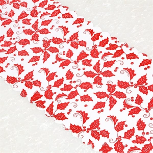 Detailed close-up of white Christmas table runner with red holly leaves and scalloped edges