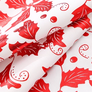Detailed view of white Christmas table runner with festive red holly and berry prints