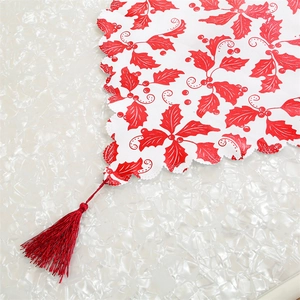 Detailed view of Christmas table runner with red holly print, lace edges and tassels