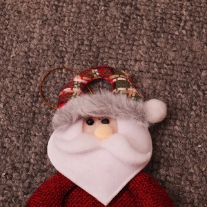 Close-up of a plush Santa Claus ornament with burlap texture and gold hanging string