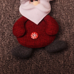 Close-up of Santa plush ornament with red burlap texture and white snowflake button