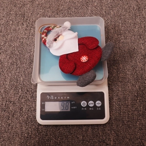 Macro shot of 9.8g Santa Claus plush ornament with snowflake button on a scale